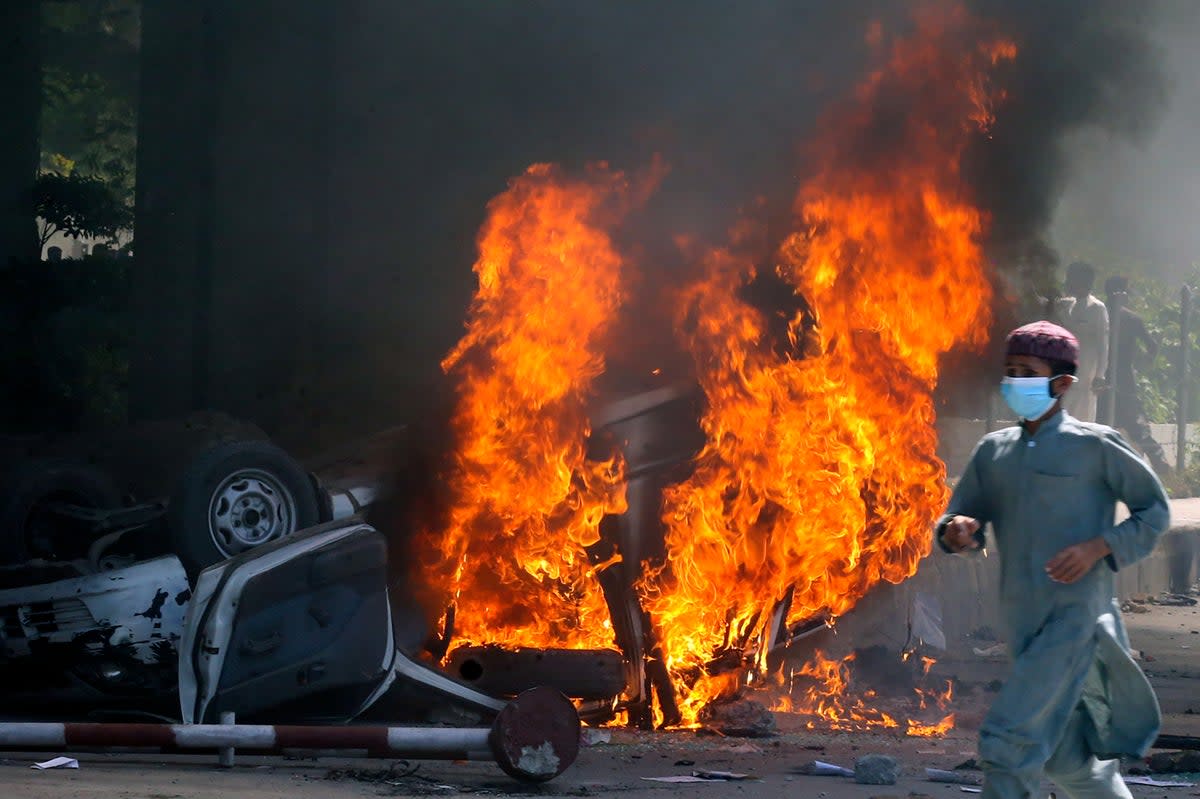 A burning car set on fire by  supporters of Pakistan's former Prime Minister Imran Khan who are angry at his arrest   (AP)