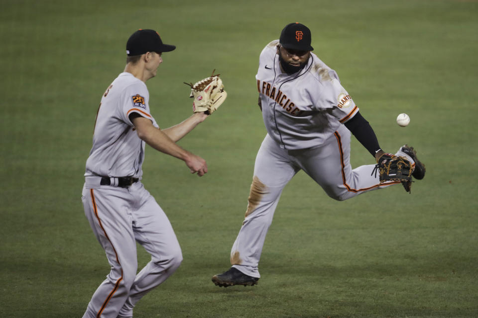 San Francisco Giants' Pablo Sandoval, right, tosses the ball to relief pitcher Tyler Rogers for the out on Los Angeles Dodgers' Max Muncy at first base during the eighth inning of a baseball game Sunday, July 26, 2020, in Los Angeles. (AP Photo/Jae C. Hong)