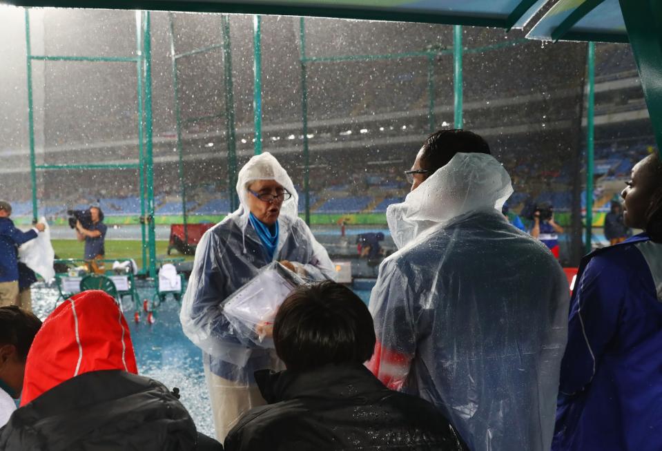 <p>Competitors wait under an awning as rain falls at the Olympic Stadium. (Getty) </p>