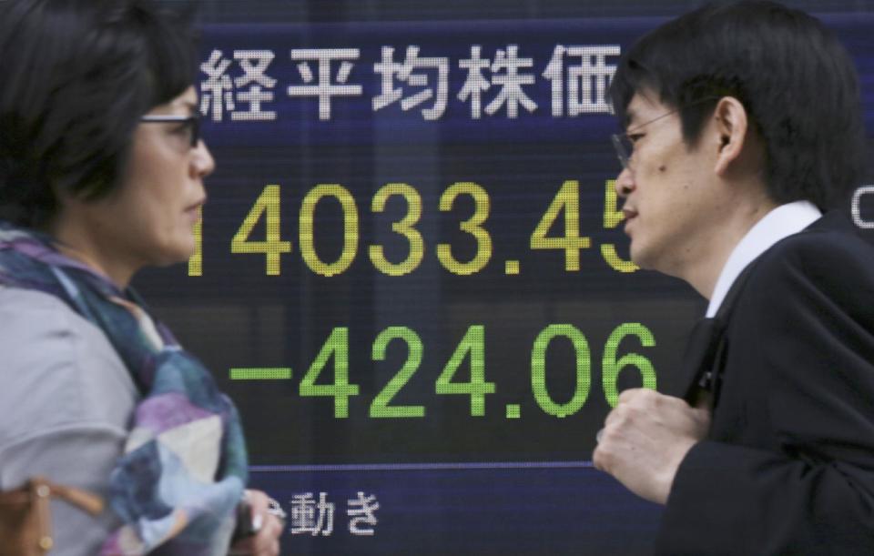 People walk by an electronic stock board of a securities firm in Tokyo, Wednesday, May 7, 2014. A dismal day on Wall Street spilled over into Asian trading Wednesday as jitters over the valuations of technology companies contributed to a sharp drop in Japan's benchmark. The Nikkei 225 stock index fell 2.3 percent to 14,120.25. Japanese markets were closed the previous two days for public holidays. (AP Photo/Eugene Hoshiko)