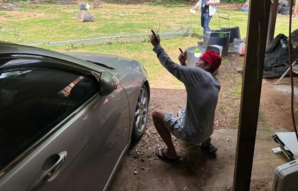 Saing Chhoeun, 54, shows how an officer took cover behind a sedan parked in his driveway and fired at the house next door during an incident April 29, 2024, in Charlotte, North Carolina.