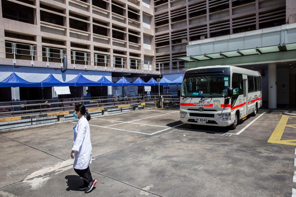 A hospital worker walks outside Queen Elizabeth Hospital in Hong Kong on March 10, 2022, as the government announced the hospital will be used only for Covid-19 patients. (Photo by ISAAC LAWRENCE / AFP) (Photo by ISAAC LAWRENCE/AFP via Getty Images)