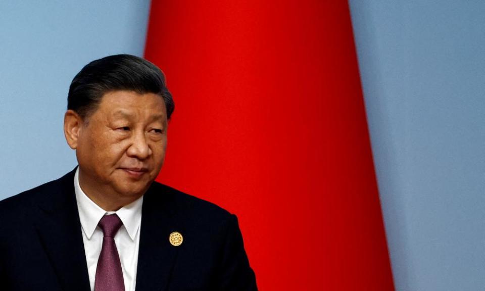 Xi Jinping looking pensive in front of a dfurled Chinese flag