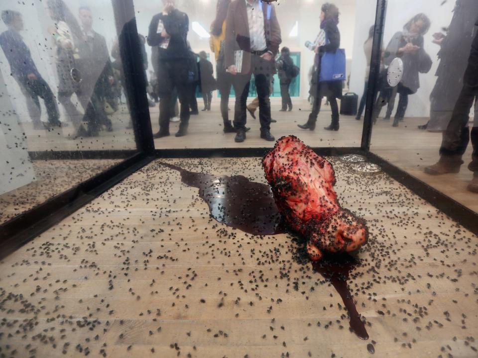 People view a fly-covered cow's head, part of an artwork by Damien Hirst entitled 'A Thousand Years' in the Tate Modern art gallery on April 2, 2012 in London, England.