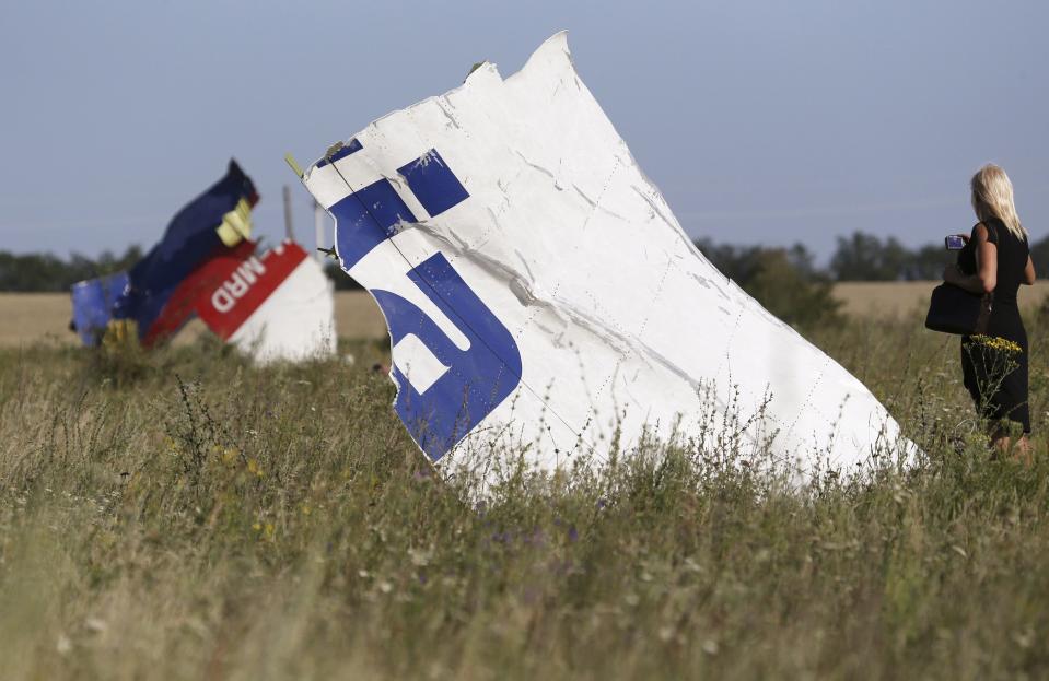A woman takes a photograph of wreckage at the crash site of Malaysia Airlines Flight MH17 near the village of Hrabove (Grabovo), Donetsk region July 26, 2014. Nearly 300 people, 193 of them Dutch citizens, were killed when the Malaysia Airlines plane en route from Amsterdam to Kuala Lumpur was brought down in eastern Ukraine, where separatists are battling government forces, on July 17. REUTERS/Sergei Karpukhin (UKRAINE - Tags: POLITICS DISASTER TRANSPORT CIVIL UNREST TPX IMAGES OF THE DAY)