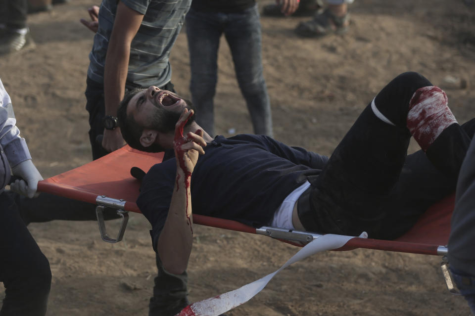 Palestinian medics carry a wounded protester during a protest at the Gaza Strip's border with Israel, Friday, Oct. 5, 2018. (AP Photo/Khalil Hamra)