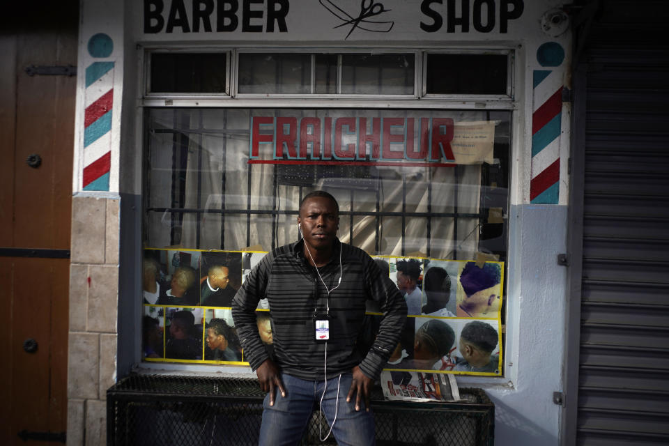 Philocles Julda, 44, poses for a photo in front of a Haitian barbershop in Tijuana, Mexico, Thursday, Nov. 22, 2018. Julda is part of a group of Haitian immigrants who started the Association of the Defense of Haitian Migrants to give the community a place to help itself with everything from Spanish lessons to paying medical bills. (AP Photo/Ramon Espinosa)