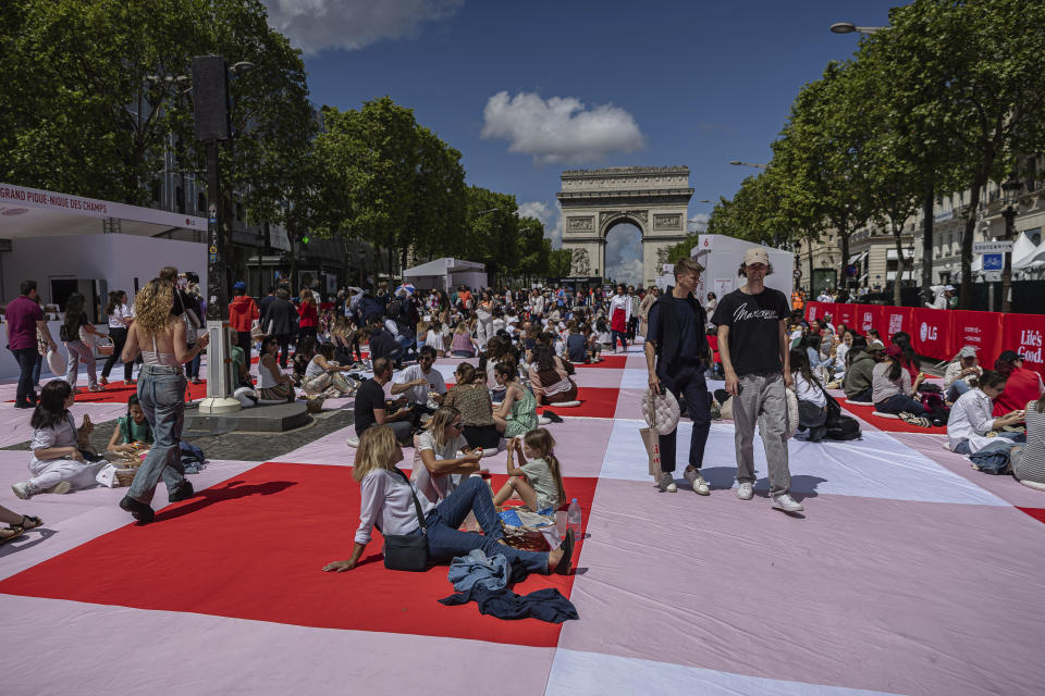 People eat their lunches as part of a giant picnic on the Champs-Elysées, in front of the Arc de Triomphe, organized by the Comité Champs-Élysées, Sunday, May 26, 2024 in Paris. (AP Photo/Aurelien Morissard)