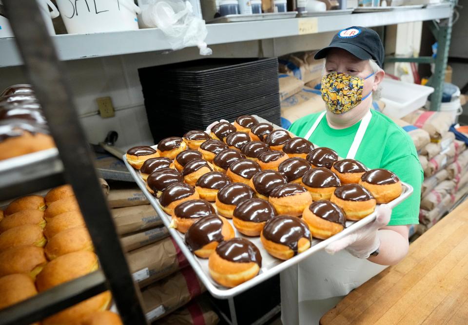 Kim Drost, the sister of Lakeside Bakery owner, Karen Kreig, stacks a tray of freshly iced chocolate Bavarian cream paczki in preparation for Paczki Day or Fat Tuesday at Lakeside Bakery on East Oklahoma Avenue in Milwaukee on Monday. The bakery has prepared 6,500 paczki to sell. The filled Polish doughnuts, pronounced POONCH-key, are typically available on the day before Ash Wednesday for Shrove Tuesday.