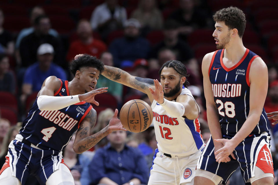 Detroit Pistons forward Isaiah Livers (12) reaches to knock away a pass intended for Houston Rockets guard Jalen Green (4) as Rockets center Alperen Sengun, right, screens during the first half of an NBA basketball game Friday, March 31, 2023, in Houston. (AP Photo/Michael Wyke)