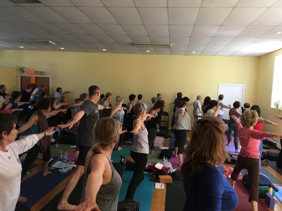 A packed room full of people doing yoga.