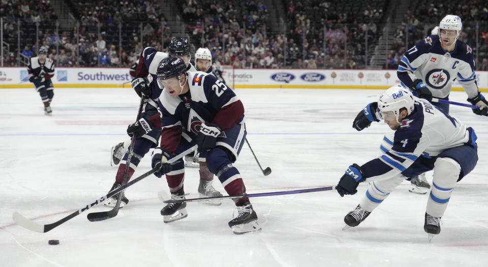 Colorado Avalanche right wing Logan O'Connor, left, collects the puck as Winnipeg Jets defenseman Neal Pionk covers during the first period of an NHL hockey game Thursday, Dec. 7, 2023, in Denver. (AP Photo/David Zalubowski)