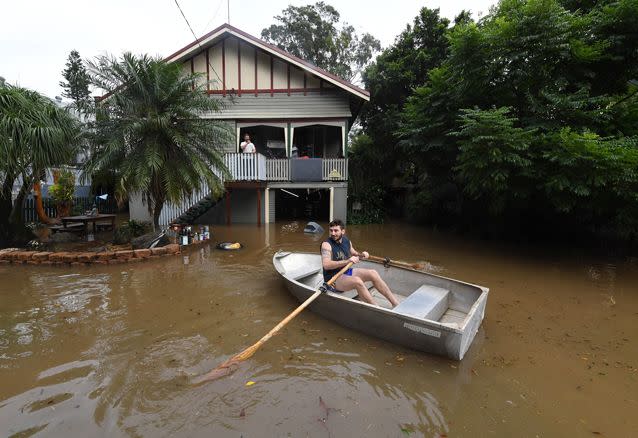 Lennon Bartlett paddles a rowboat to his parents house next door to where he lives in central Lismore. Picture: AAP