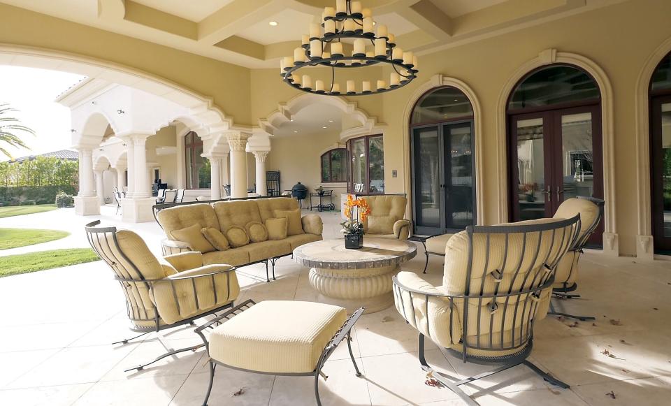 A different patio with more seating and a giant three-tiered chandelier that holds countless candles