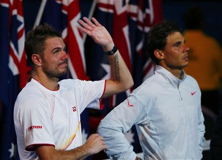 Stanislas Wawrinka of Switzerland waves as he stands next to Rafael Nadal (R) of Spain after winning their men's singles final match at the Australian Open 2014 tennis tournament in Melbourne January 26, 2014. REUTERS/Petar Kujundzic