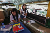 Grade school student Bhea Joy Roxas, left, uses a nearby store's wifi signal so she can join the online opening of classes from inside a passenger jeepney at the Tandang Sora jeepney terminal in Quezon city, Philippines on Monday, Oct. 5, 2020. Grade and high school students in the Philippines have started classes at home after the pandemic forced remote-learning onto an educational system already struggling to fund schools. (AP Photo/Aaron Favila)
