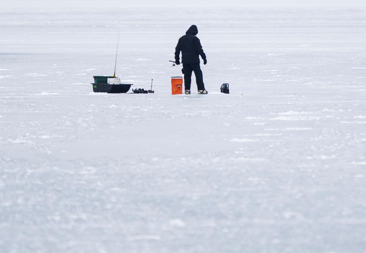 A person ice fishes on Juno Lake in Edwardsburg a year ago in January 2021. This year, ice on many lakes is forming different-colored patches, reflecting how it can be inconsistent.