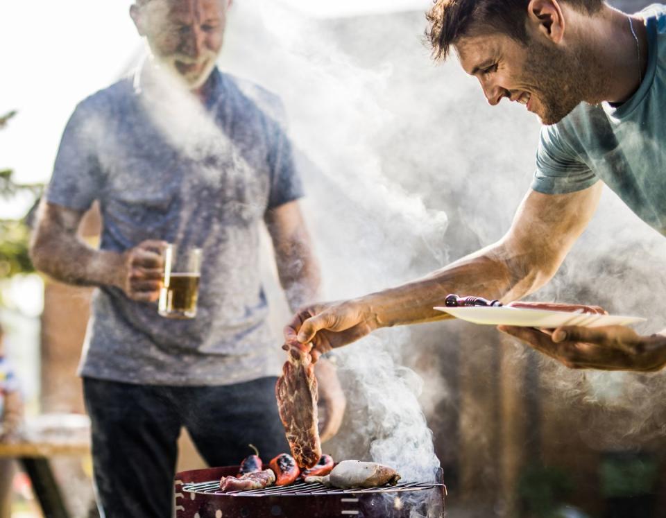 happy man grilling meat on a barbecue grill outdoors