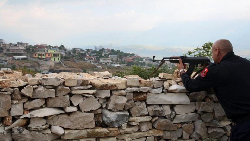 Un oficial de policía albanesa asegura el perímetro de una casa en Lazarat, un pueblo conocido como la capital europea del cannabis, al sur de la capital albanesa Tirana, el 18 de junio de 2014