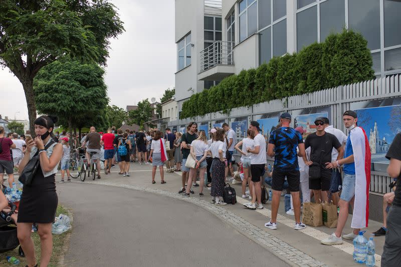 People queue outside the Belarusian embassy to cast their votes during the presidential election in Warsaw