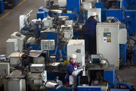 An employee looks up as she works at a production line at a Wanxiang electric vehicle factory in Hangzhou, Zhejiang province, January 22, 2014. REUTERS/Aly Song