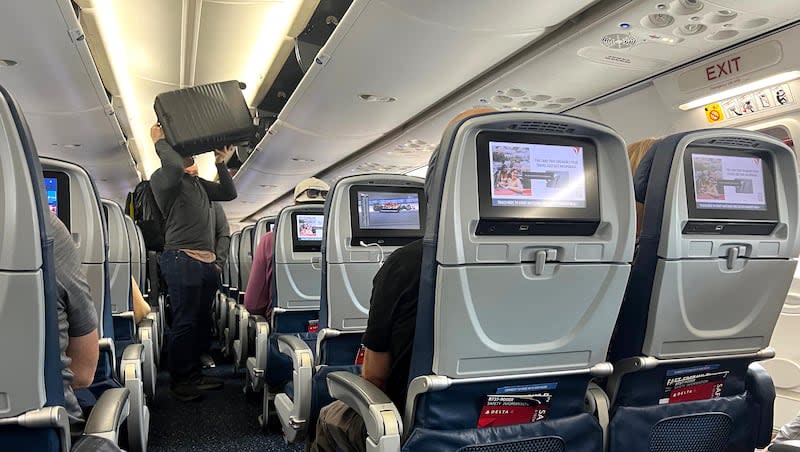 A passenger loads his carry-on suitcase in an overhead compartment on a Delta Airlines flight at Salt Lake City International Airport Saturday, March 2, 2024.