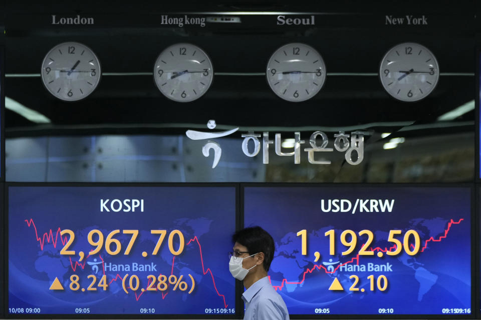 A currency trader passes by screens showing the Korea Composite Stock Price Index (KOSPI), left, and the foreign exchange rate between U.S. dollar and South Korean won at the foreign exchange dealing room of the KEB Hana Bank headquarters in Seoul, South Korea, Friday, Oct. 8, 2021. Asian stocks followed Wall Street higher Friday after U.S. lawmakers temporarily averted a possible government debt default while investors waited for American jobs numbers. (AP Photo/Ahn Young-joon)