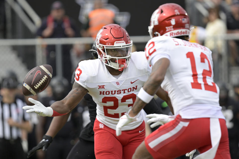 Houston running back Parker Jenkins (23) flips the ball to wide receiver Stephon Johnson (12) on a reverse play during the first half of an NCAA college football game against Central Florida, Saturday, Nov. 25, 2023, in Orlando, Fla. (AP Photo/Phelan M. Ebenhack)