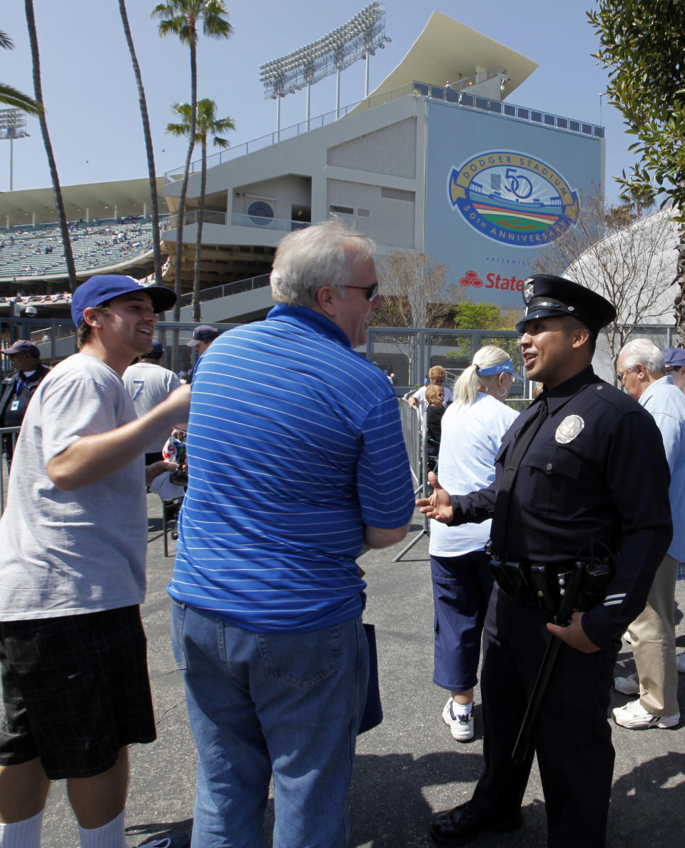 Los Angeles Police Officer Mel Campos chats with Dodger fans arriving for the home opener baseball game at Dodger Stadium Tuesday, April 10, 2012. Police were out in force, swarming on bikes, going undercover and cracking down on boozing tailgaters a year after a Giants fan was beaten into a coma in the parking lot. (AP Photo/Reed Saxon)