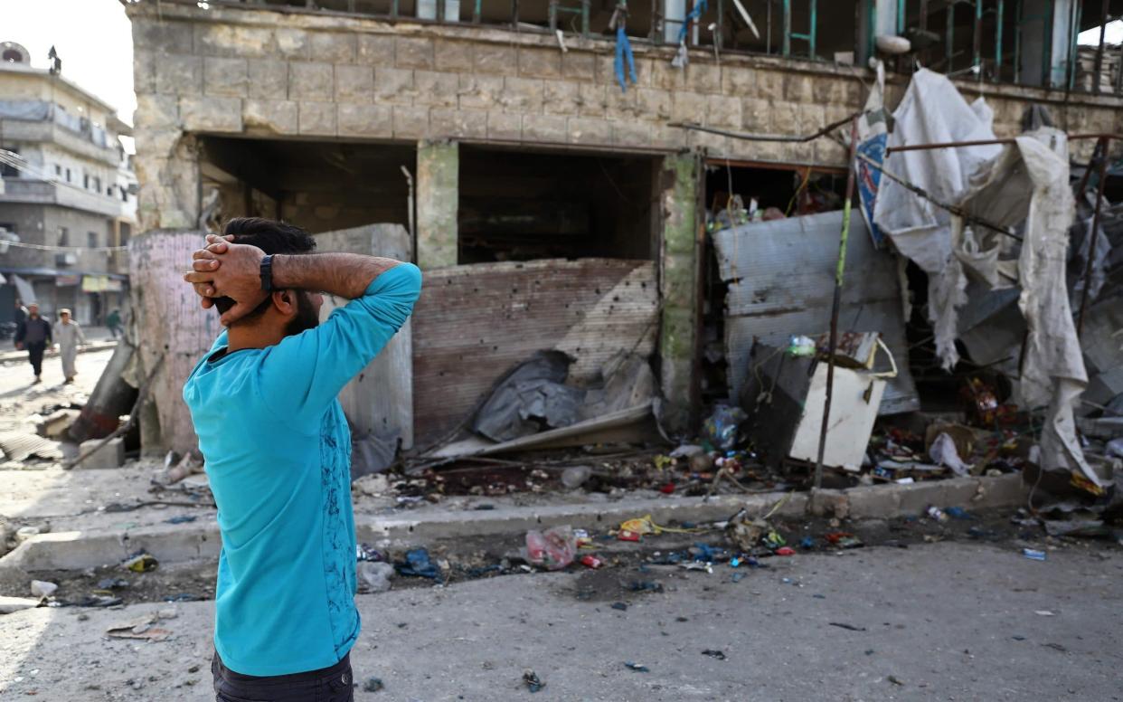 People gather at the site of an air strike on a market in the town of Maarat al-Numan in Idlib - AFP