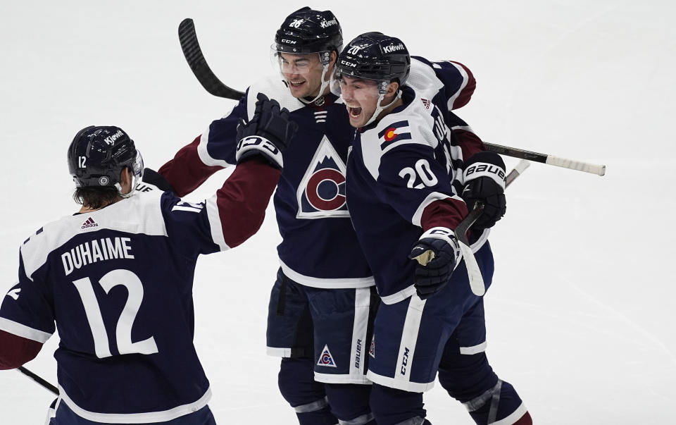 Colorado Avalanche defenseman Sean Walker, center, celebrates after scoring a goal with right wing Brandon Duhaime (12) and center Ross Colton (20) in the first period of an NHL hockey game against the Dallas Stars Sunday, April 7, 2024, in Denver. (AP Photo/David Zalubowski)