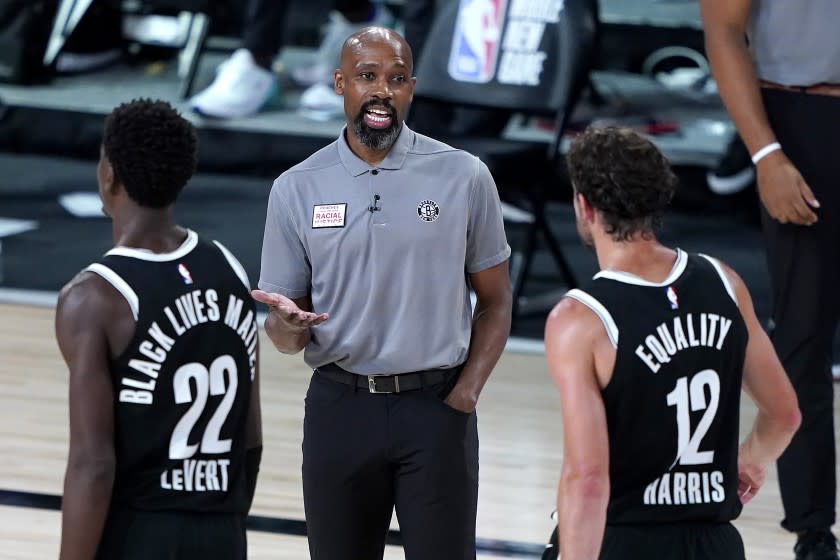 Brooklyn Nets head coach Jacque Vaughn, center, talks with Joe Harris (12) during a timeout.