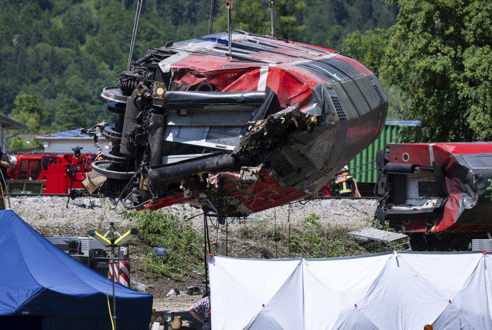 A carriage is being lifted on the site of a train crash in Burgrain, near Garmisch-Partenkirchen, Germany, Saturday, June 4, 2022. Authorities say a train accident in the Alps in southern Germany on Friday left at least four people dead and many more injured. Police said the regional train headed for Munich appears to have derailed shortly after noon in Burgrain — just outside the resort town of Garmisch-Partenkirchen, from where it had set off. Three of the double-deck carriages overturned at least partly, and people were pulled out of the windows to safety. (Sven Hoppe/dpa via AP)
