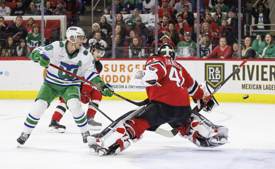 Carolina Hurricanes' Sebastian Aho (20) scores the game-winning goal against New Jersey Devils' goaltender Vitek Vanecek (41) in overtime of an NHL hockey game in Raleigh, N.C., Saturday, Feb. 10, 2024. (AP Photo/Ben McKeown)