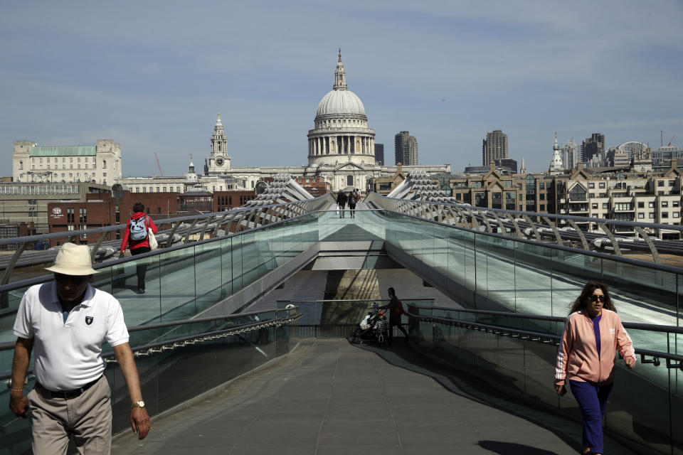 People space out to observe social distancing, on the Millennium Bridge backdropped by St Paul's Cathedral in London, during the lockdown to try and stop the spread of coronavirus, Wednesday, April 15, 2020. The British government is promising to test thousands of nursing home residents and staff for the new coronavirus, as it faces criticism for failing to count care-home deaths in its tally of victims. (AP Photo/Matt Dunham)