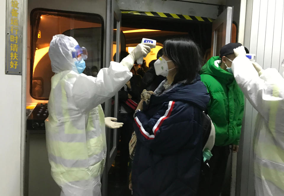 Funcionarios de salud revisan la temperatura corporal de los pasajeros que llegan de la ciudad de Wuhan al aeropuerto de Beijing, el miércoles 22 de enero de 2020. (AP Foto Emily Wang)