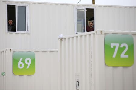 Migrants look out of the windows of a shipping container converted into a home at a state-run shelter near Calais, northern France, February 21, 2016. REUTERS/Pascal Rossignol