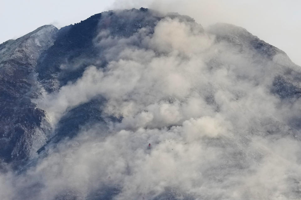 Mayon volcano spews steam as seen from Daraga town, Albay province, northeastern Philippines, Tuesday, June 13, 2023. Truckloads of villagers on Tuesday fled from Philippine communities close to gently erupting Mayon volcano, traumatized by the sight of red-hot lava flowing down its crater and sporadic blasts of ash. (AP Photo/Aaron Favila)