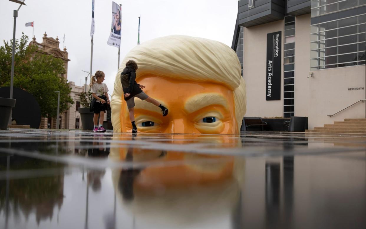 An 11-year-old boy kicks an art piece in the form of Trump's head in Australia - REUTERS