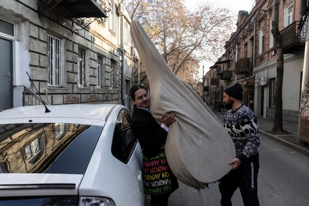 A taxi driver helps Antropov to take out his double bass from the car (Reuters)