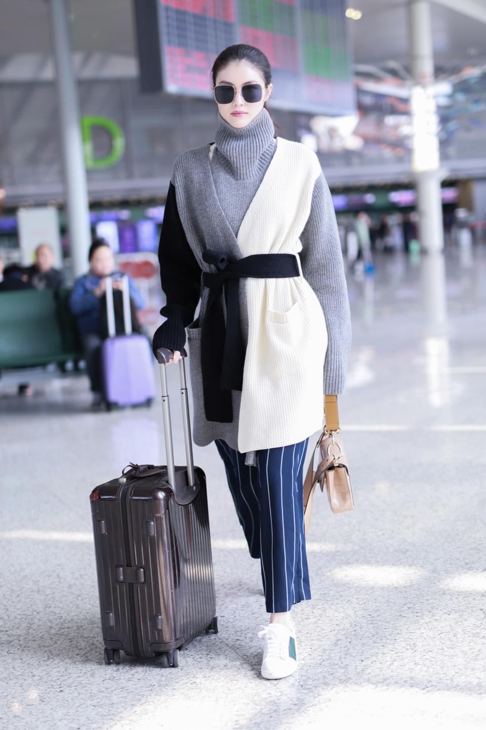 Bundling up for the airplane has never been so chic. With an oversize cardigan, funnel-neck sweater, and pajama suiting pants, you're ready—and comfortable—for transit.