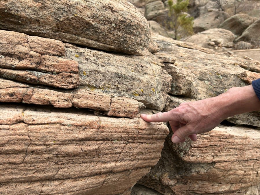 Dr. Mark Longman pointing at a layered sandstone in the opal-cemented Castle Rock (Joan Burleson, Denver Museum of Nature and Science)