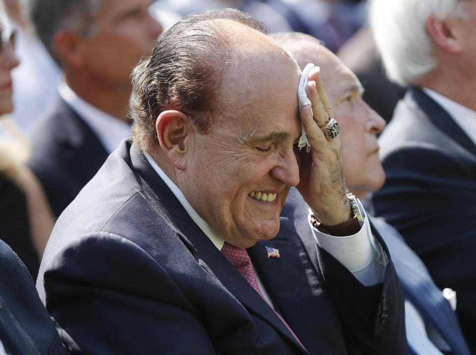 FILE - In this July 29, 2019 file photo, Rudy Giuliani, an attorney for President Donald Trump, left, wipes his forehead as he listens to President Donald Trump speak in the Rose Garden of the White House in Washington. (AP Photo/Pablo Martinez Monsivais)