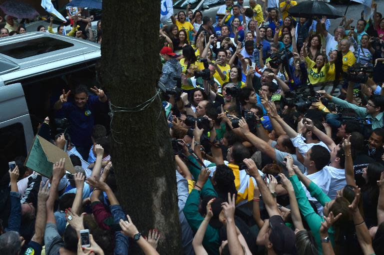 Brazilian presidential candidate for the Brazilian Social Democracy Party (PSDB) Aecio Neves(L inside van) flashes a V sign to supporters in Belo Holizonte, Brazil, on October 26, 2014