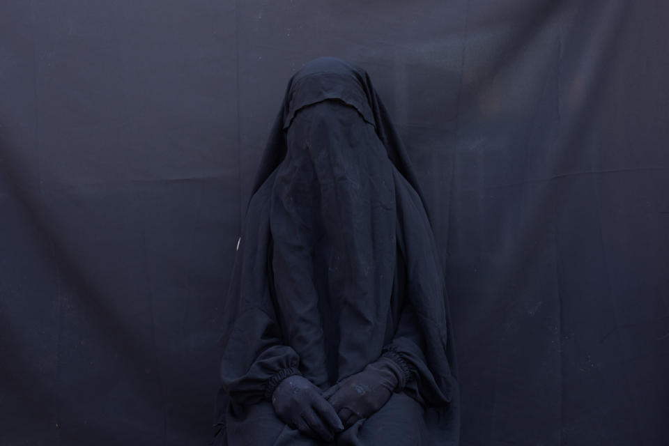 In this Sept. 9, 2019 photo, Yazidi Layla Taloo poses for a portrait in the full-face veil and abaya she wore while enslaved by Islamic State militants, at her home in Sharia, Iraq. Taloo's 2 1/2-year ordeal in captivity underscores how IS members continually ignored the rules the group tried to impose on the slave system. "They explained everything as permissible. They called it Islamic law. They raped women, even young girls," said Taloo, who was owned by eight men. (AP Photo/Maya Alleruzzo)