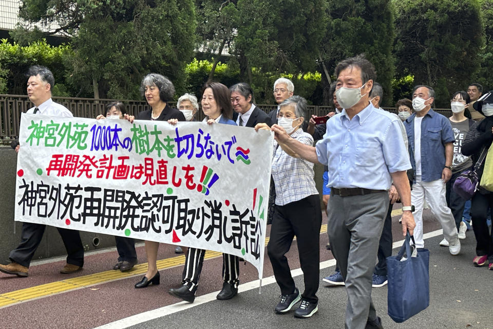 Plaintiffs suing the Tokyo Metropolitan Government to stop its approval of a controversial redevelopment plan for a historic and beloved park area, march into the Tokyo District Court in Tokyo, Thursday, June 29, 2023. A banner reads, “Please do not cut 1,000 trees at Jingu Gaien.” Critics of the planned redevelopment of the beloved centuries-old Tokyo park and historic sports stadiums accused the government in court on Thursday of ignoring the wishes of residents and catering to commercial interests. (AP Photo/Haruka Nuga)