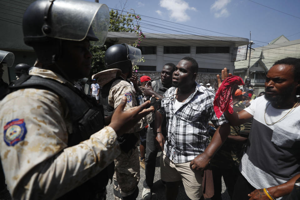 Police in riot gear block demonstrators from marching to the President's house during anti-government protests in Port-au-Prince, Haiti, Friday, Oct. 11, 2019. Protesters burned tires and spilled oil on streets in parts of Haiti's capital as they renewed their call for the resignation of President Jovenel Moïse just hours after a journalist was shot to death. (AP Photo/Rebecca Blackwell)