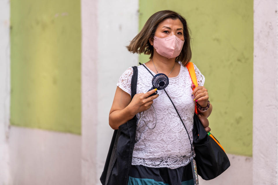 HONG KONG, CHINA - 2023/05/30: A woman uses a USB fan to cool herself in Quarry Bay as an amber alert for extreme heat is issued. The Hong Kong Observatory recently launched a new weather alert system to warn residents about the health risks of extreme heat, advising them to seek shelter and drink more water. (Photo by Ben Marans/SOPA Images/LightRocket via Getty Images)