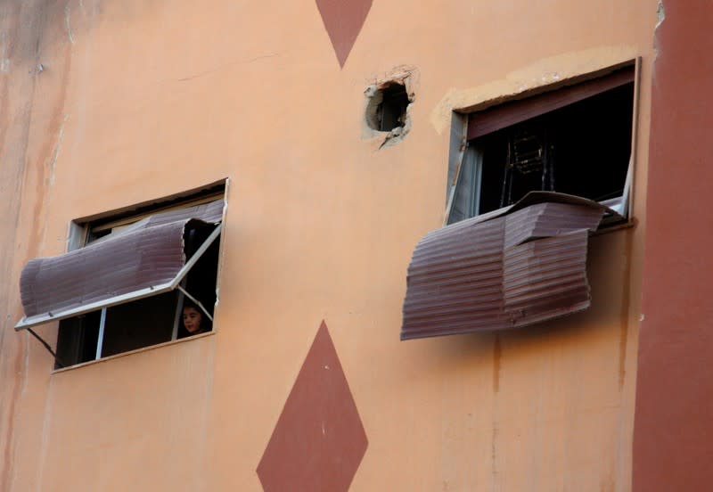 Boy looks out the window of a building, damaged from an Israeli attack in Damascus