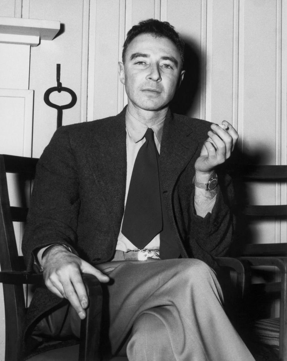 j robert oppenheimer, wearing a suit and tie and holding a cigarette, looking directly into the camera